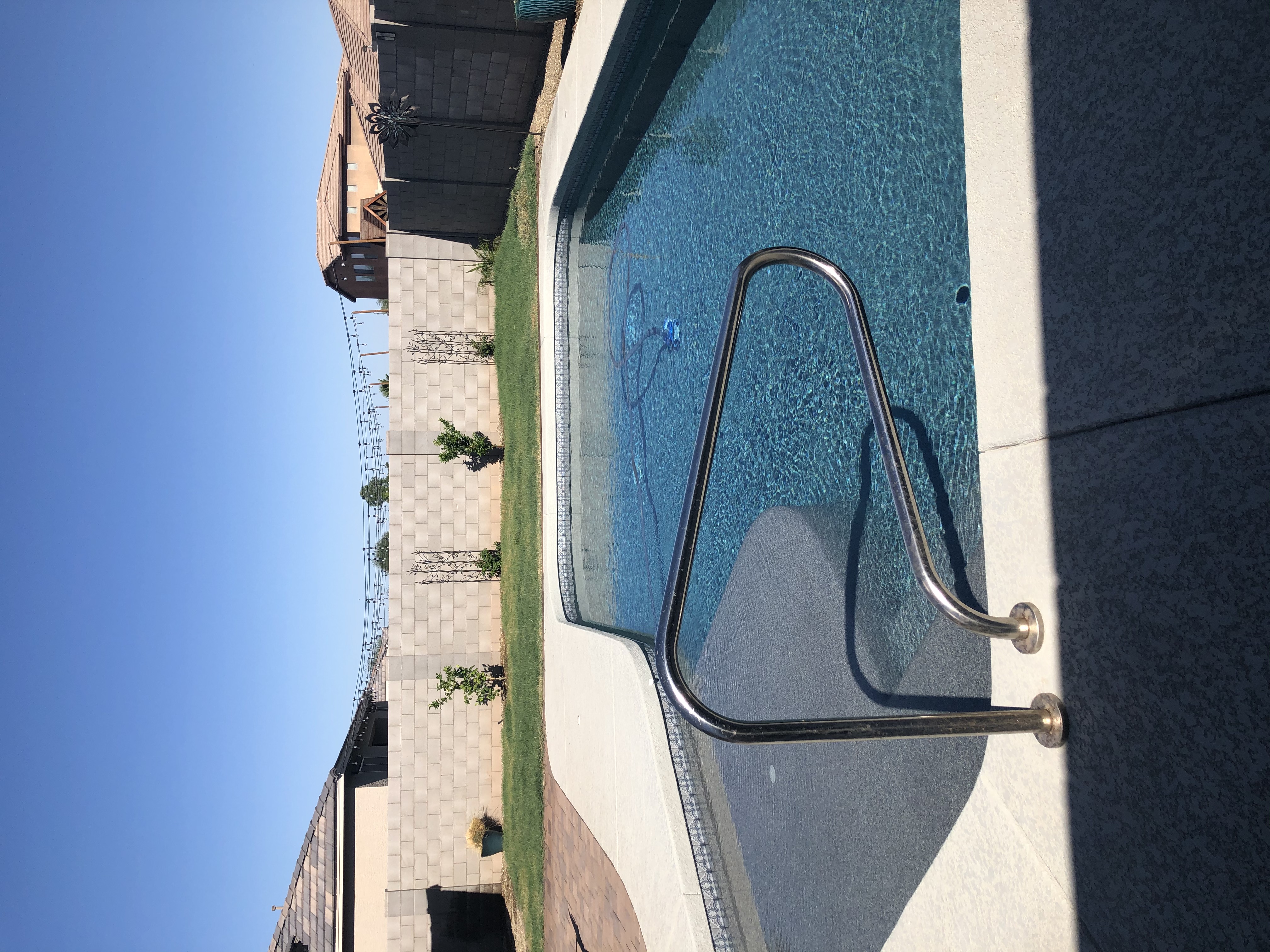 Classic residential pool refresh with broad deck space, curved swim entry, and clear blue water